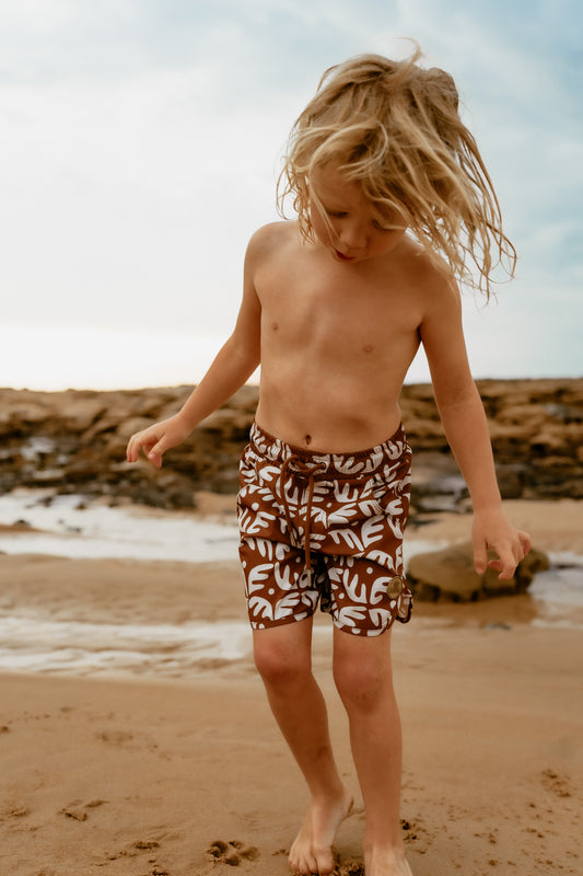 Kohv wearing the brown and tan coral board shorts by Australian surf brand Kohvi Kids for boy aged 1-10.
